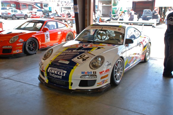 White, blue and yellow striped Justice Brothers Porsche GT3 cup car #94_garage 2_3/4 front view_California Festival of Speed_April 6, 2013